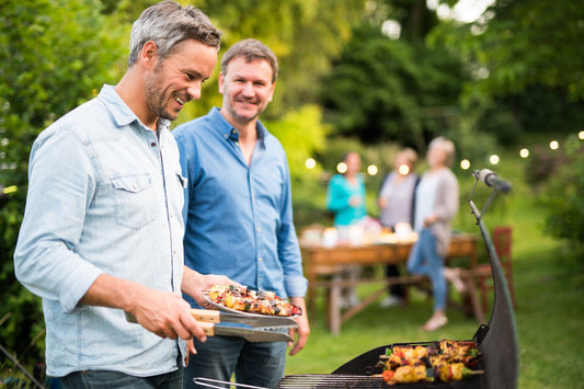 Two middle-aged men in their 40s grill together at an outdoor party. Gut changes can be challenging for men over 40. Learn more in our guide.