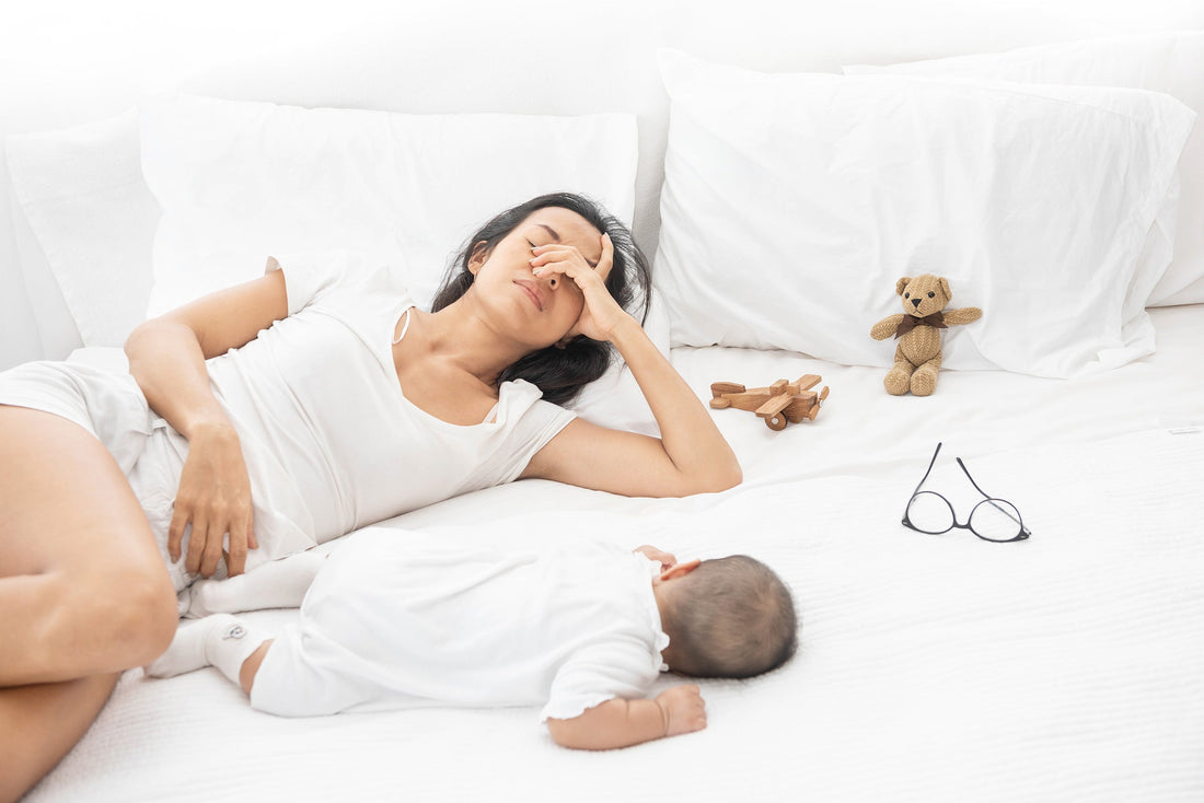 A new mom with her baby on a bed. Postpartum gas is nearly universal — and lasts up to 4 weeks. Here's why it happens after any delivery type, plus relief strategies and what to wear.
