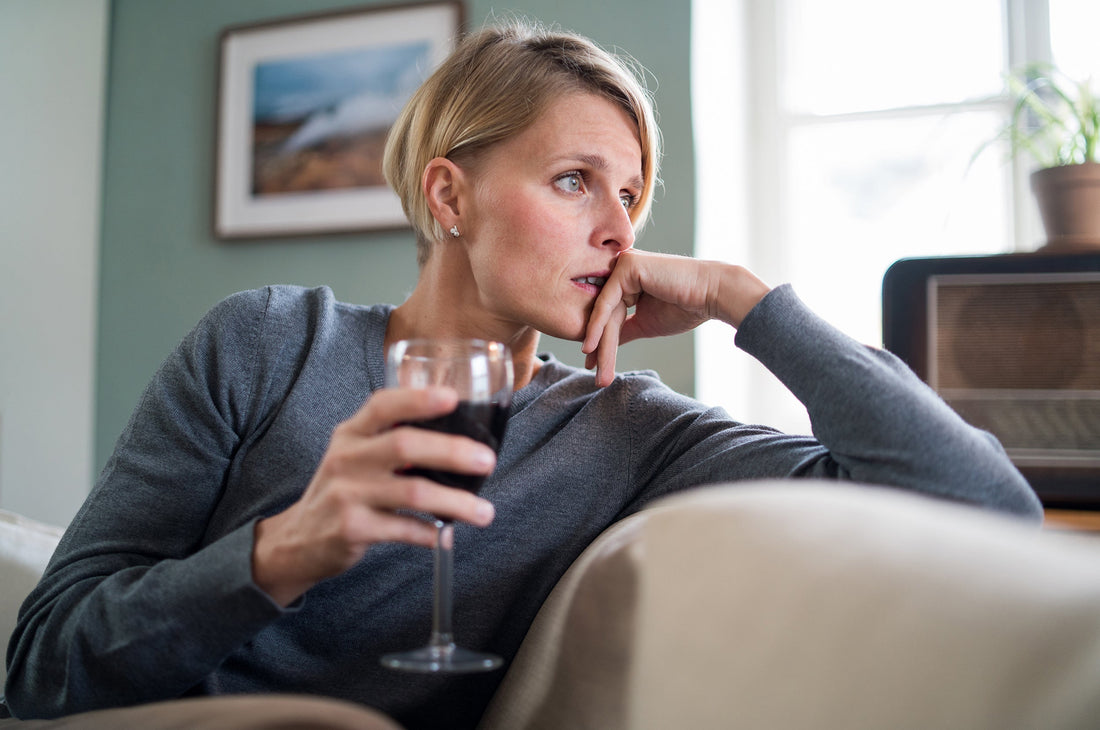 A woman drinks wine on the couch. Can alcohol cause IBS? Learn more about the alcohol-IBS connection in our complete guide.