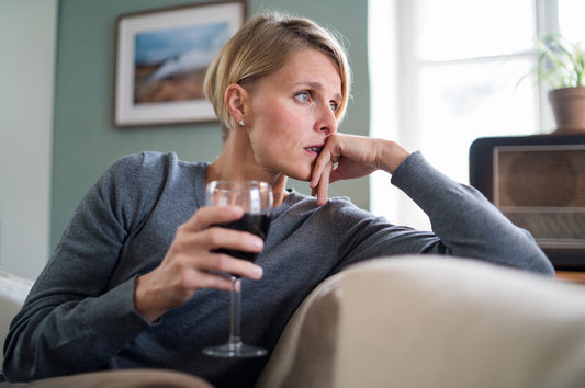 A woman drinks wine on the couch. Can alcohol cause IBS? Learn more about the alcohol-IBS connection in our complete guide.