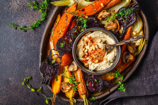 Hummus dip surrounded by vegetables. Does hummus make you gassy? Learn why chickpeas cause gas and more in our complete guide.