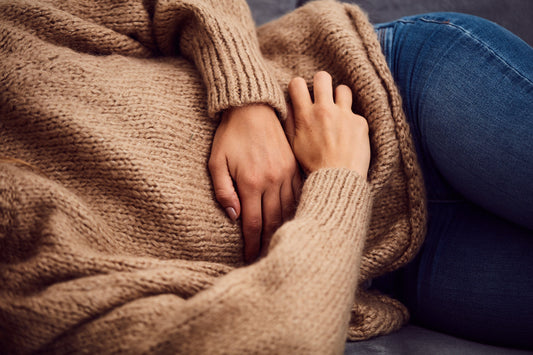A woman holds her stomach. Endo belly can make you look visibly pregnant by midday. Understand the endometriosis-digestion connection and find strategies that go beyond cutting out dairy.
