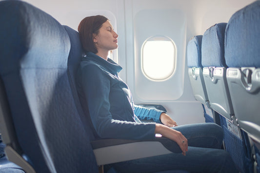 A woman on a plane. IBS and air travel are a rough combination. Discover why flying triggers symptoms and get practical strategies for every stage of the journey.
