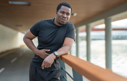 A man clutches his stomach while running. Runner's gut affects up to 90% of distance runners. Learn why it happens, what triggers it, and how to manage symptoms — so nothing slows you down mid-race.