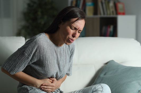 A woman clutches her stomach in pain. Why am I so gassy at night? Food reaches your colon for fermentation 6-8 hours after eating, peaking right at bedtime. Learn causes and solutions.